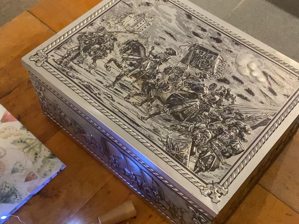 Una caja plateada con relieves tallados, sobre la mesa del encuentro.